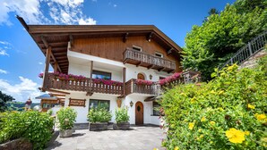 Un chalet tradicional con fachada de madera, un balcón con jardineras y un patio empavedado.