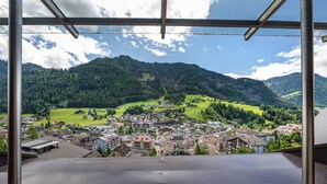 Vista desde una ventana sobre un pueblo situado en un valle, con montañas al fondo.