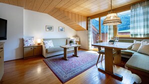 Una habitación acogedora con techo de madera, un sofá, una mesita y una ventana con cortinas.