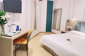 A hotel room with a bed, desk, chair, and a TV mounted on the wall. - Chidao Hotel (Beijing Nanjiao Cancer Hospital Branch) (Beijing)