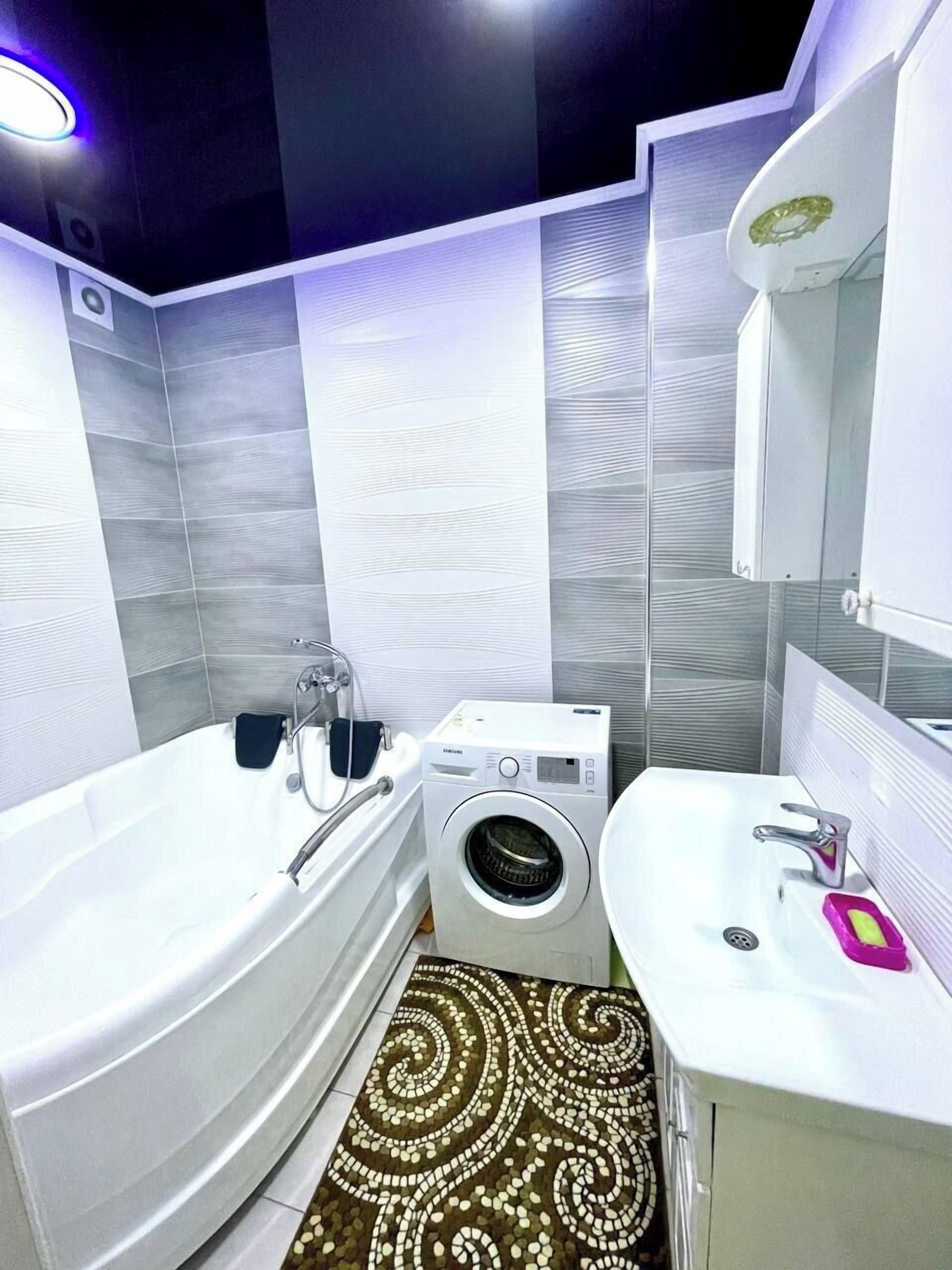 A modern bathroom with a bathtub, a washing machine, and a sink.