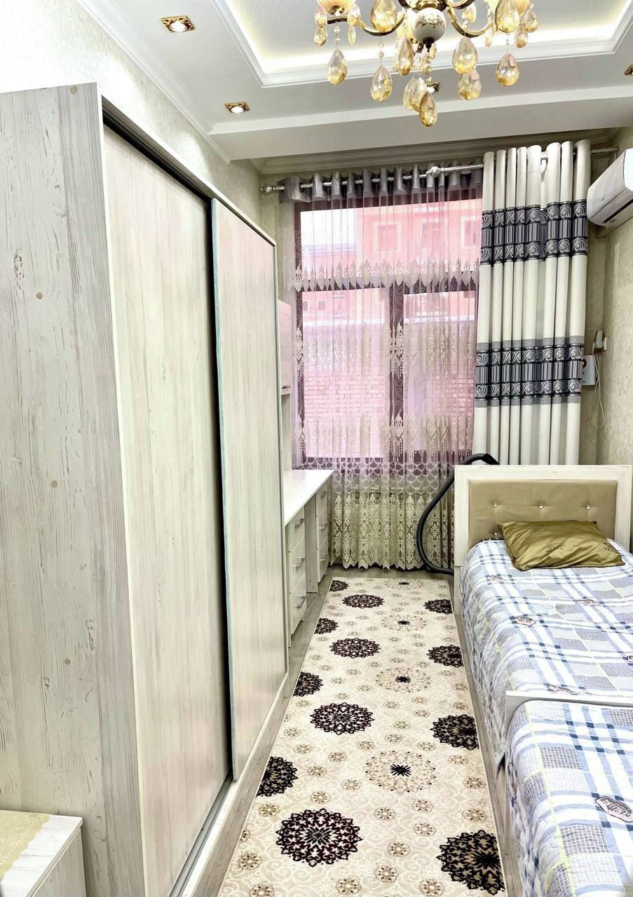 Une chambre à coucher avec un lit, une armoire, une fenêtre avec des rideaux et un sol à motifs.
