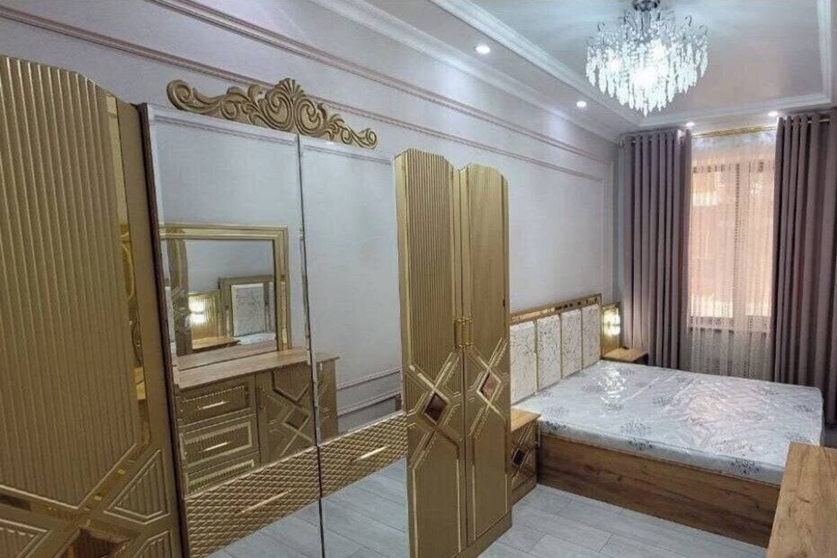 A bedroom with a large bed, a wardrobe with mirrored doors, and a chandelier.