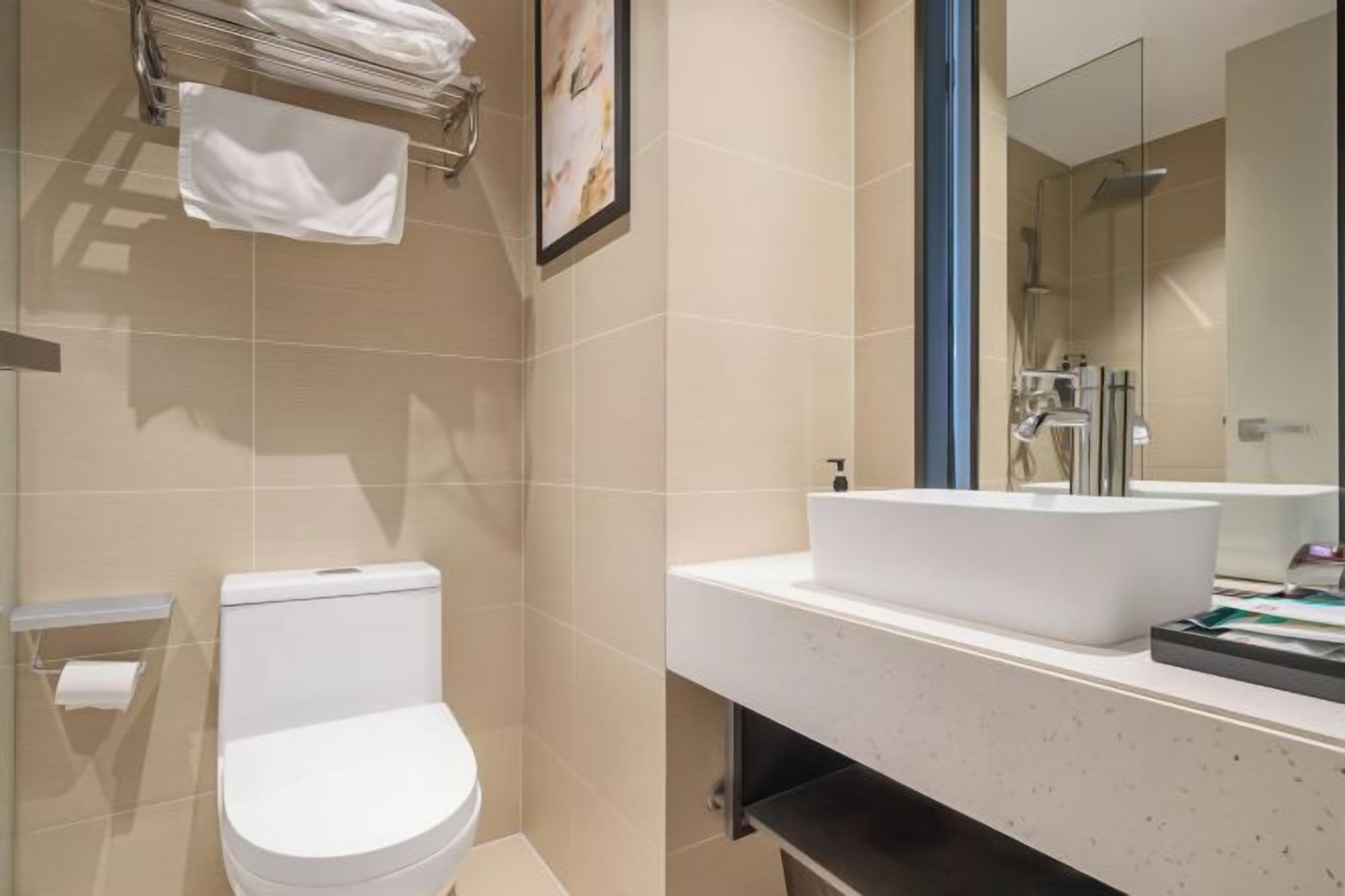 A bathroom with a toilet, sink, and mirror.