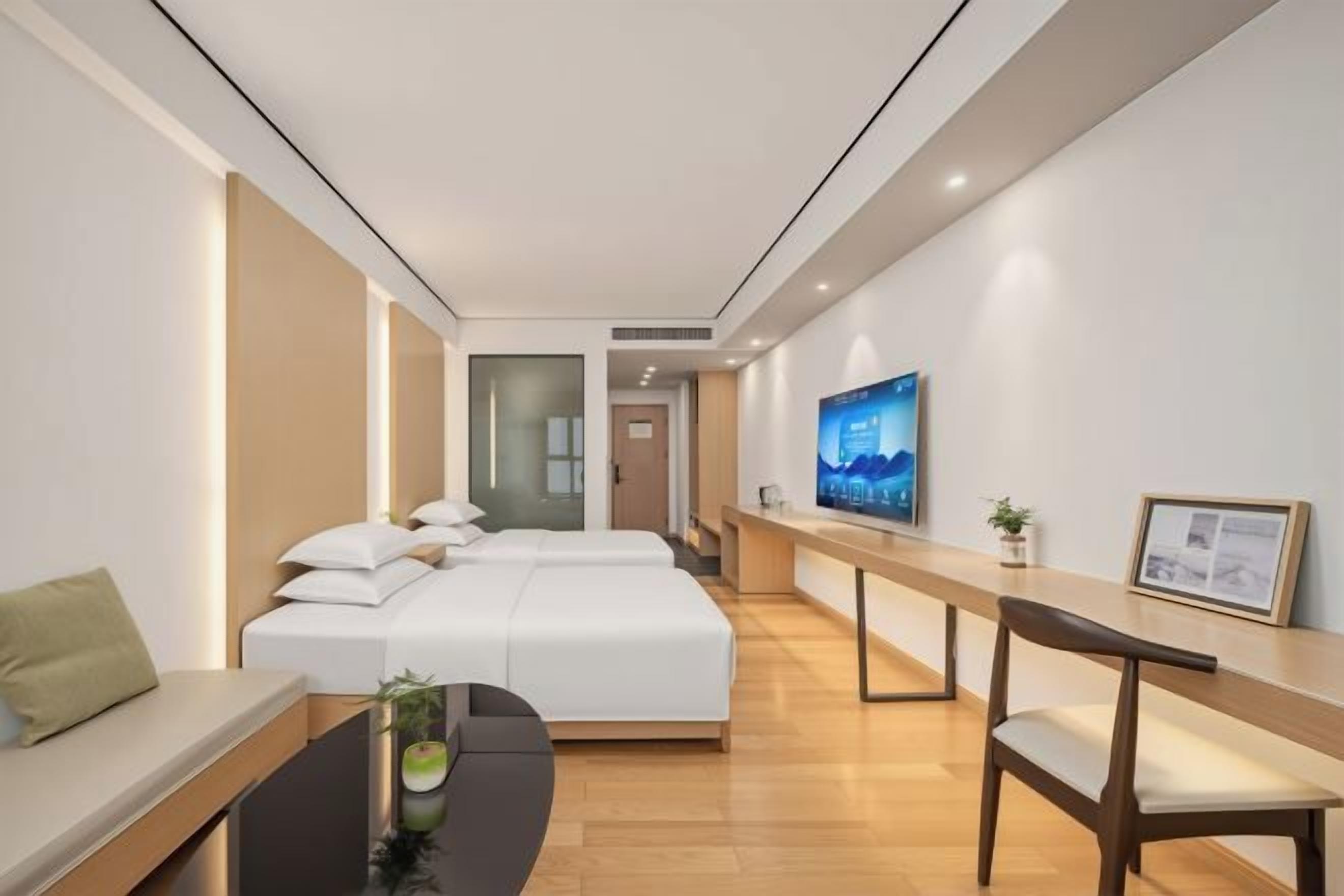 Une chambre d’hôtel moderne équipée d’un lit, d’un bureau, d’une chaise et d’un téléviseur.