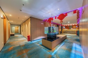 A hotel lobby with a reception desk, a fish tank, and a patterned carpet.