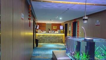 Um hall de hotel com uma mesa de recepção, um aquário e uma parede de pedra.
