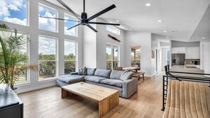 Ein geräumiges Wohnzimmer mit Ecksofa, Couchtisch aus Holz und Deckenventilator.