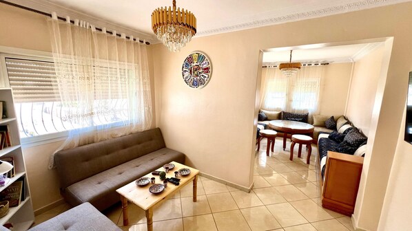 A living room with a sofa, a coffee table, and a dining area with a table and chairs.