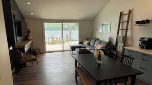 A modern living space with a dining area, sofa, and a view of the outdoors. - Swim, Sip, and Stay Awhile at this Beautiful Keuka Lake Retreat! (Dundee)