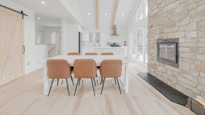 A modern kitchen with white cabinets, a stone accent wall, and a built-in fireplace.