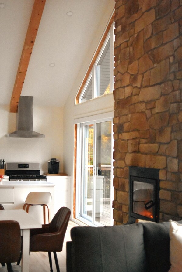 A modern kitchen with a stone wall, a fireplace, and a dining area with chairs and a table.