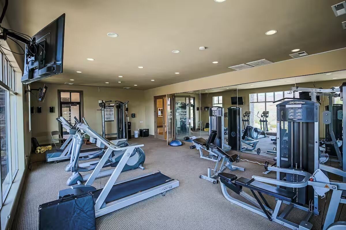 A gym with treadmills, weight machines, and a mirrored wall.