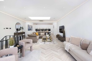A modern living room with a sofa, armchairs, a coffee table, and a TV. - 1 Min Walk to Harrods | Knightsbridge Duplex (London)