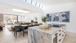 A spacious living area with a marble island, modern furniture, and abstract wall art.