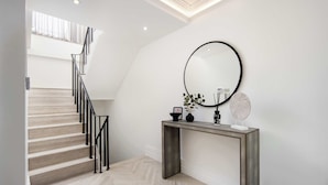 A staircase with a modern design, a console table with a mirror, and a fan.