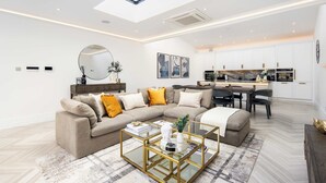 A modern living room with a sofa, coffee table, and a dining area with chairs.