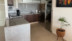 A modern kitchen with granite countertops, stainless steel appliances, and a central island. -  Phenomenal ocean view  2bed, 2 bath Apartment. (Cancún)