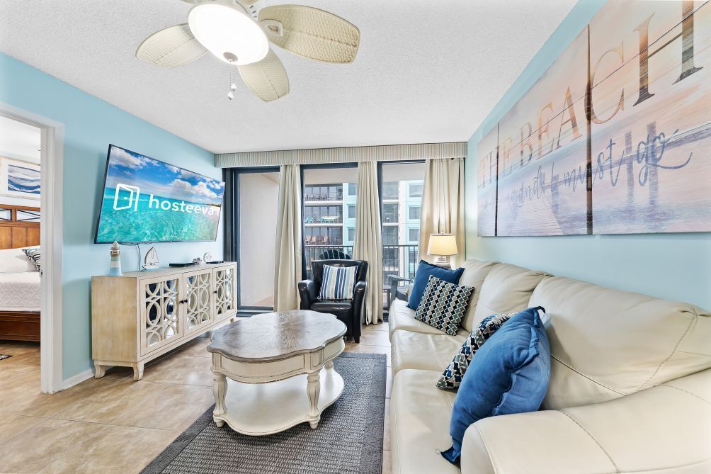 A living room with a sofa, a coffee table, a TV, and a painting on the wall.