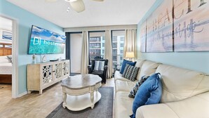 A living room with a sofa, a coffee table, a TV, and a painting on the wall. - Island Winds West 471 (Gulf Shores)