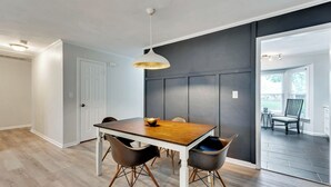 A dining area with a wooden table, two chairs, and a pendant light. - 4 Bedroom Beachside Retreat – High - Speed WiFi Included (Virginia Beach)