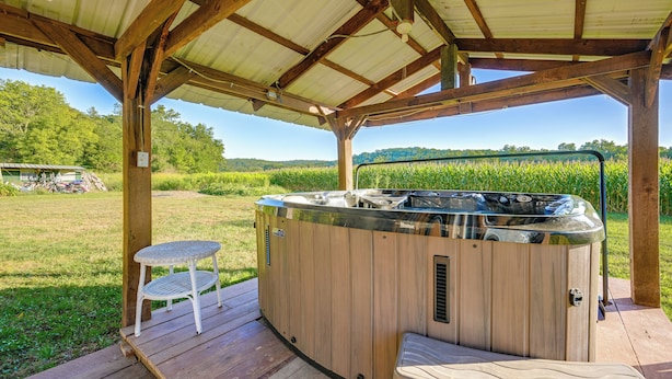 A wooden deck with a hot tub, a small table, and a bench. - Hot Tub & Creek Views: Secluded Perryville Cabin (Perryville)