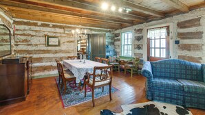 A rustic wooden interior with a dining table, chairs, a sofa, and a cowhide rug. - Hot Tub & Creek Views: Secluded Perryville Cabin (Perryville)