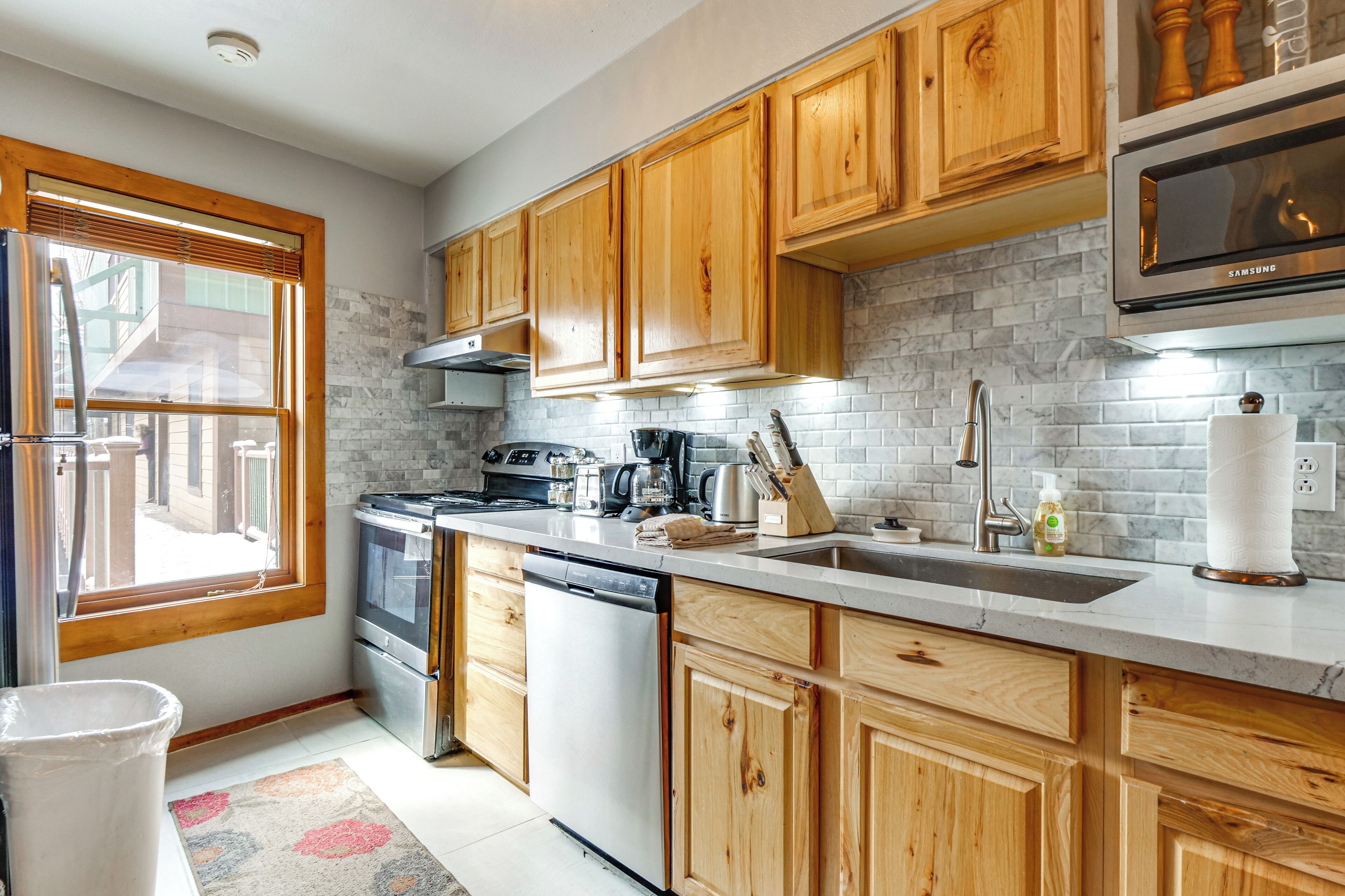 A kitchen with wooden cabinets, a stainless steel dishwasher, a built-in oven, and a microwave.