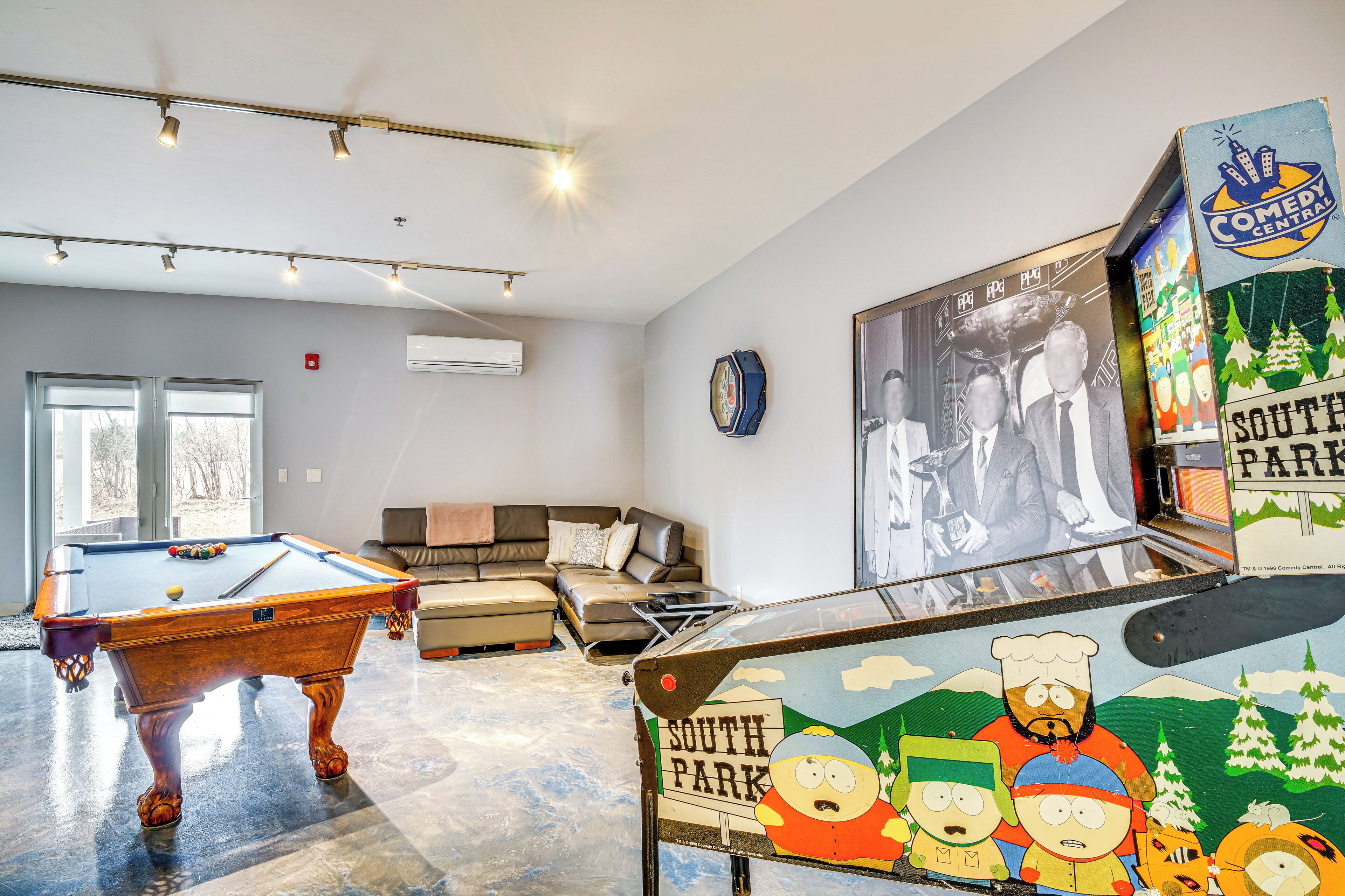 A modern living room with a pool table, a sofa, and a South Park arcade machine.