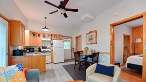 A compact living space with a kitchenette, a dining area, a sofa, and a bed. - Private Dock & Deck: Tranquil Dam Pond Cottage! (Augusta)