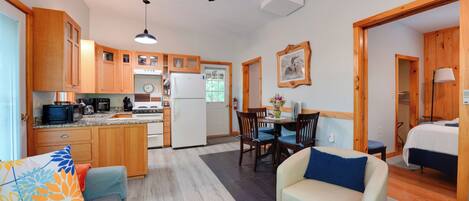 A compact living space with a kitchenette, a dining area, a sofa, and a bed.