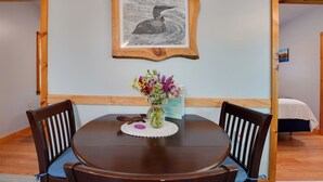 A dining table with chairs, a framed picture, and a vase with flowers. - Private Dock & Deck: Tranquil Dam Pond Cottage! (Augusta)