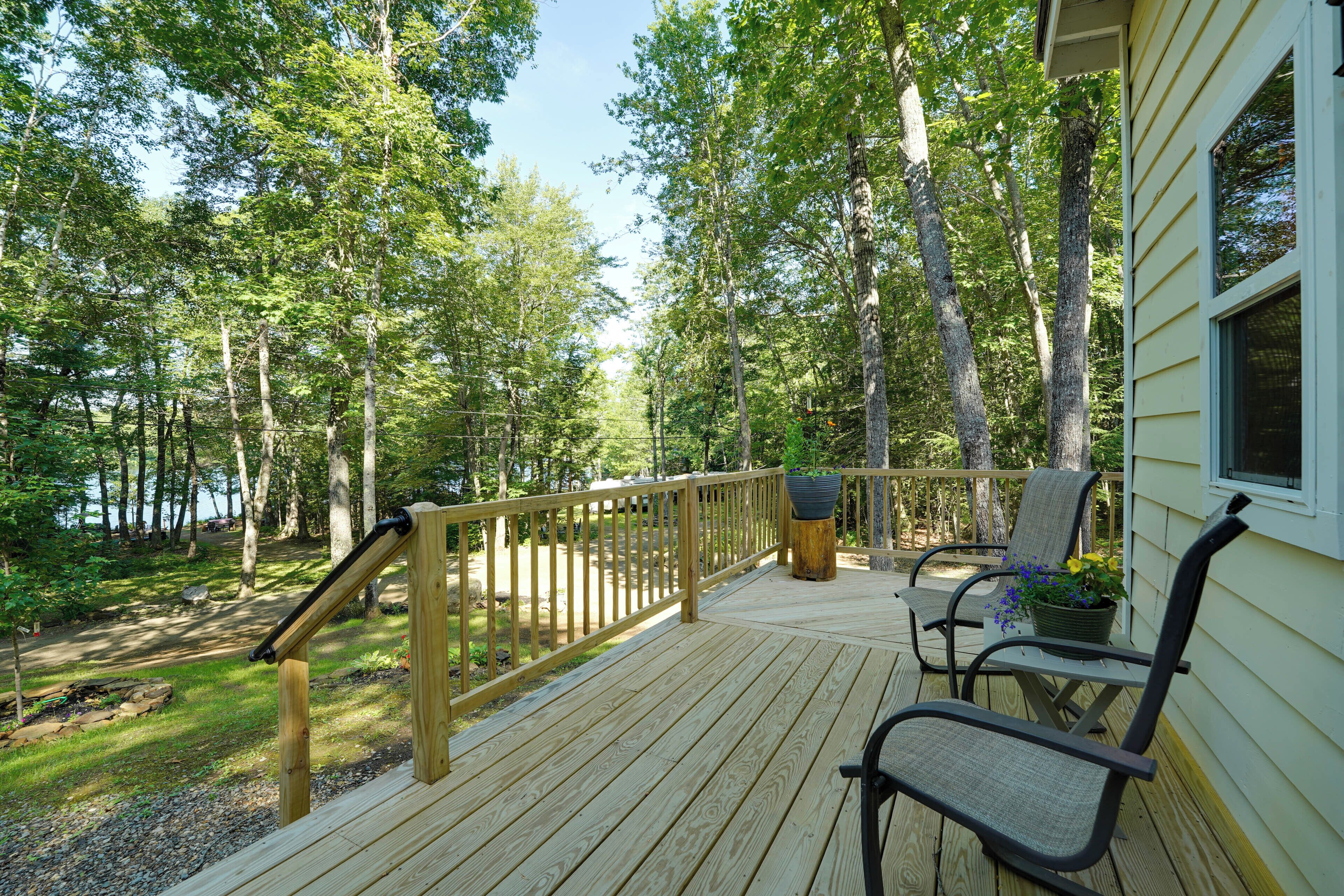A wooden deck with a railing, a bench, and a potted plant.