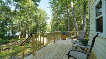 A wooden deck with a railing, a bench, and a potted plant.