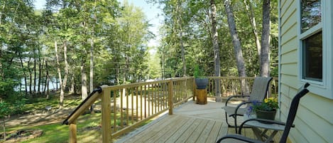 A wooden deck with a railing, a bench, and a potted plant.