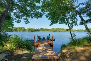A wooden dock leading to a calm lake surrounded by trees. - Private Dock & Deck: Tranquil Dam Pond Cottage! (Augusta)