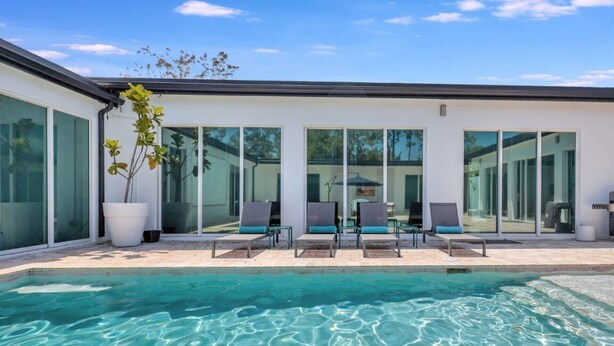 A modern pool area with clear water, lounge chairs, and large windows. - Huge Family Retreat w/ Heated Pool & Games (Westlake)