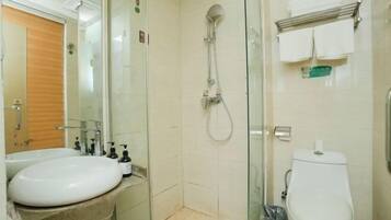 Un baño con cabina de ducha de vidrio, lavabo e inodoro.