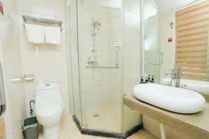 A modern bathroom with a glass-enclosed shower, a white toilet, a sink with a mirror, and a towel rack. - Shell Hotel (Xinxiang Pang Donglai Branch) (Xinxiang)