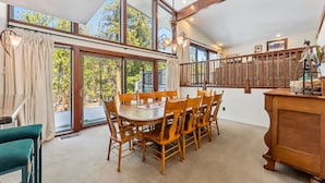 A dining area with a wooden table and chairs, large windows, and a staircase with a railing. - Spacious 4,000 Sq Ft Riverfront Home | Game Room • Deck • 1.5 Miles to Keystone (Keystone)