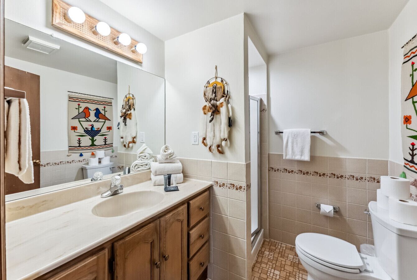 Une salle de bain avec un grand miroir, un lavabo, des toilettes et une douche.