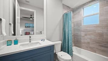 Un baño con un lavamanos blanco, armarios azules, inodoro y bañera.