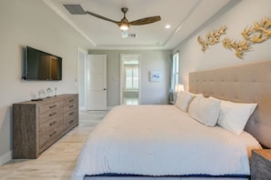 Un dormitorio con una cama, ventilador de techo, televisor, cómoda y decoración de cabeza de venado colgada en la pared.