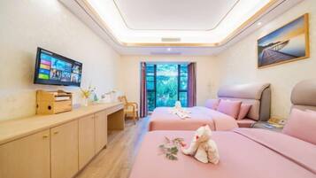 A hotel room with two beds, a desk, a television, and a window with a view of greenery.