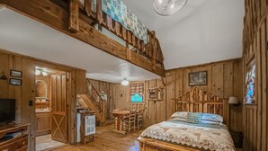 L’intérieur d’une cabane en bois comprend une chambre à coucher située en mezzanine, un coin repas et une cuisine.