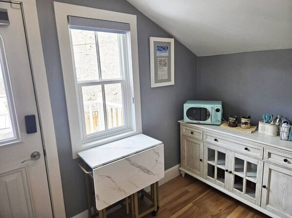 A kitchen with a white marble countertop, a vintage-style microwave, and a cabinet with glass doors.