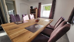 A dining area with a wooden table, purple upholstered chairs, and a window with curtains. - Vacation Home with a View of Stolpen Castle at the "Gateway to Saxon Switzerland" (Dürrröhrsdorf-Dittersbach)