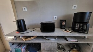 A kitchen counter with a toaster, a coffee maker, and a kettle. There are also plates, bowls, and a basket on the counter. - Vacation Home with a View of Stolpen Castle at the "Gateway to Saxon Switzerland" (Dürrröhrsdorf-Dittersbach)