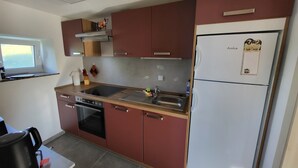 A compact kitchen with a built-in oven, a sink, and a refrigerator. - Vacation Home with a View of Stolpen Castle at the "Gateway to Saxon Switzerland" (Dürrröhrsdorf-Dittersbach)