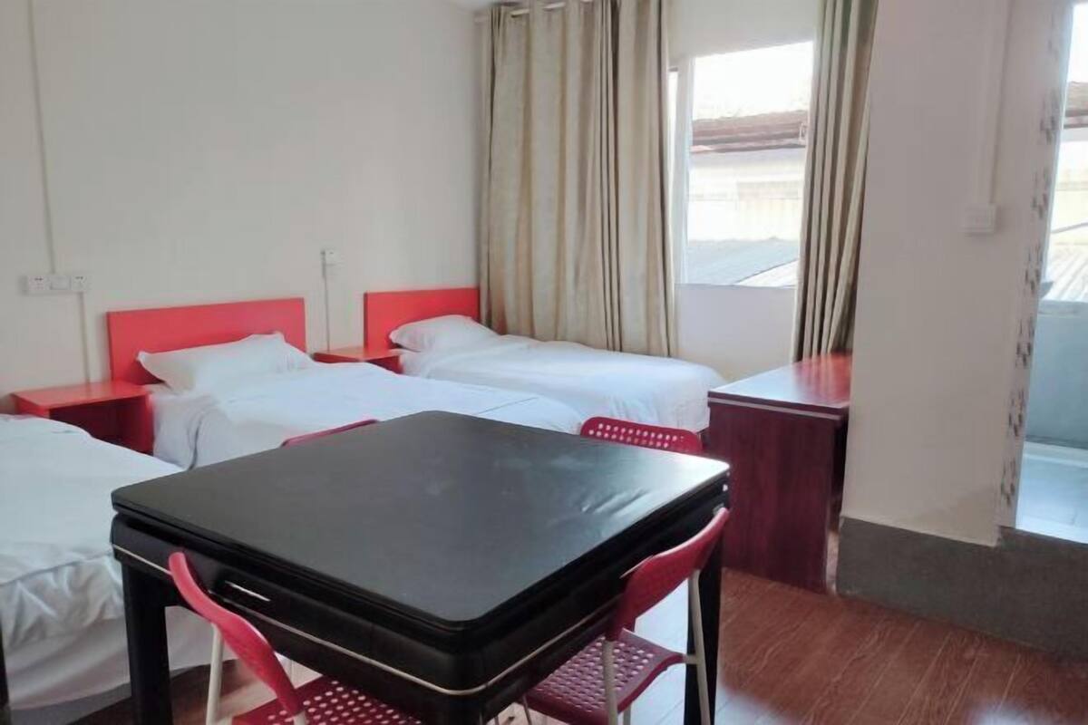Ein Hotelzimmer mit zwei Betten, einem kleinen Tisch und einem Fenster mit Vorhängen.